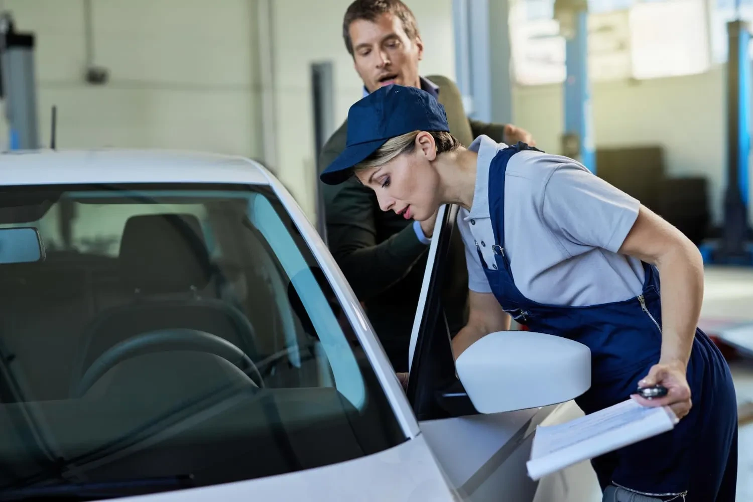 Auto glass technician inspecting a car windshield while preparing for windshield replacement or repair in a professional auto glass service shop.