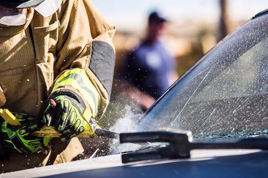 Emergency responder removing a damaged windshield from a vehicle during a professional auto glass replacement service.