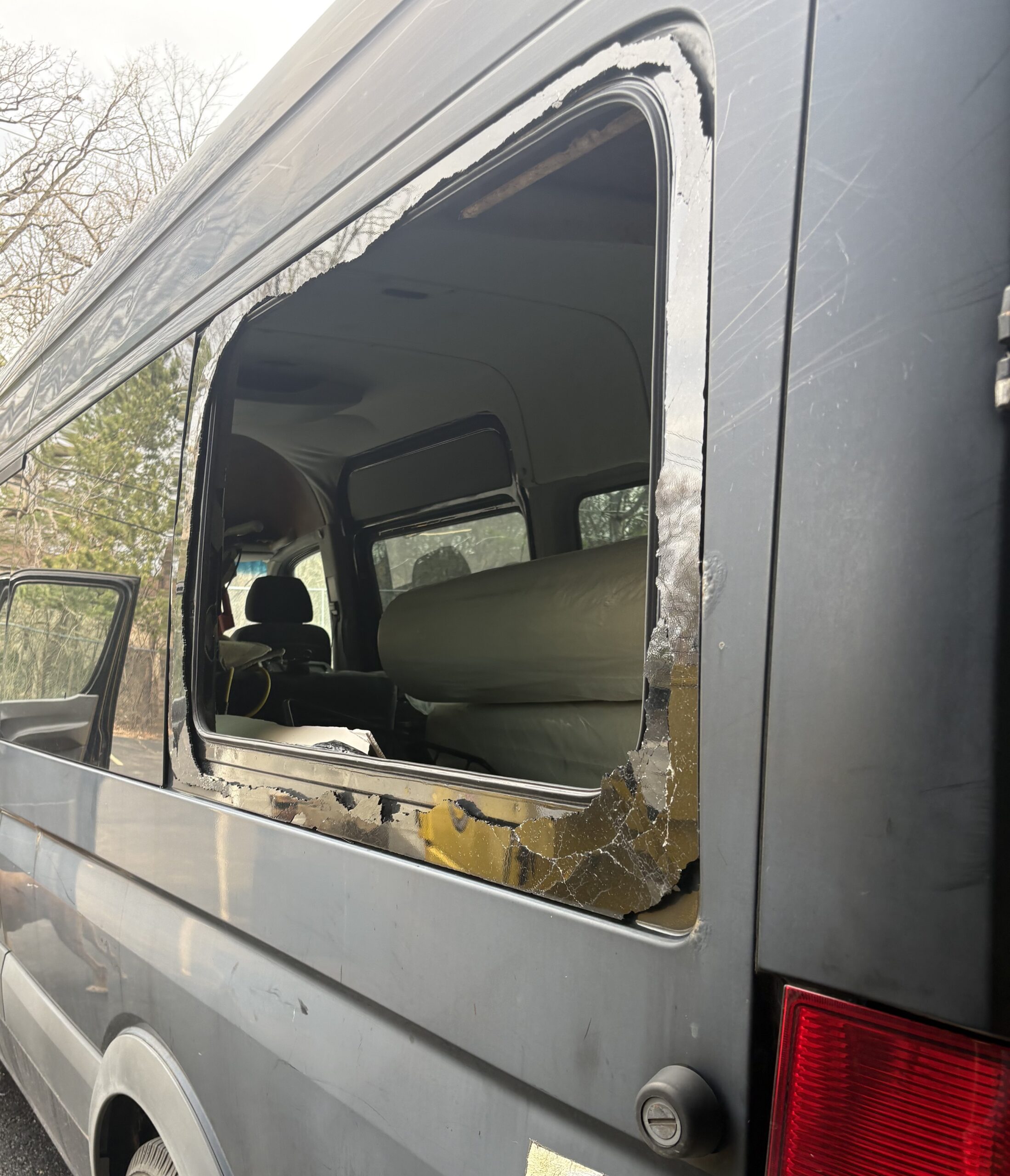 Broken side window glass on a gray van requiring car side window replacement
