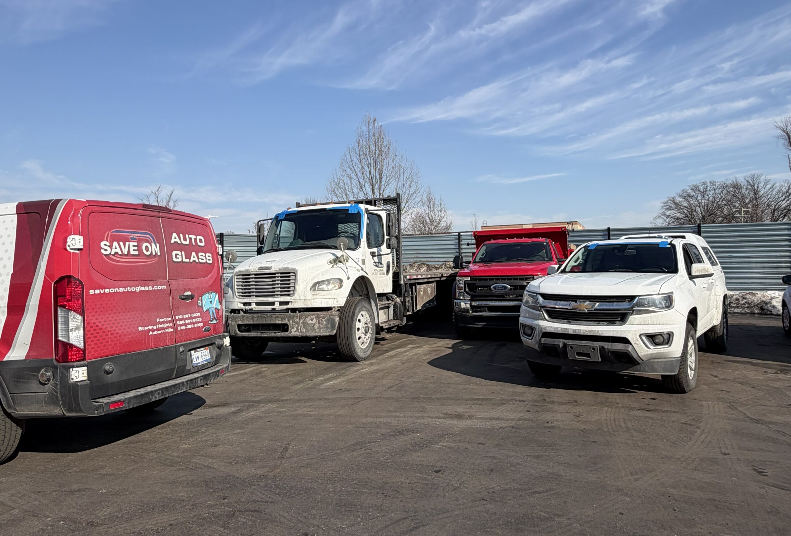 Auto glass mobile service van parked with a car and trucks after windshield replacement