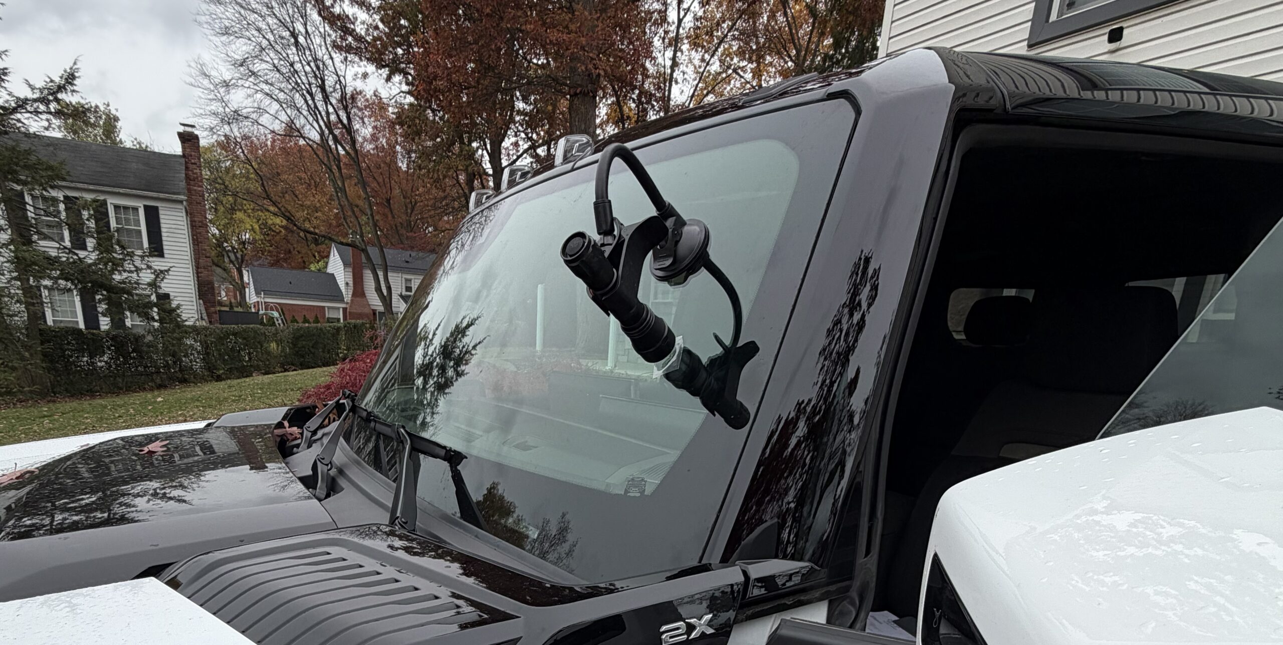 ave On Auto Glass mobile repair in progress, with a flashlight mounted on a suction-cup arm against the windshield of a dark vehicle