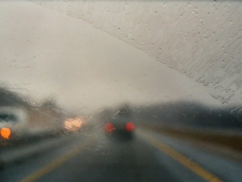 The view from a wet car windshield looking into traffic